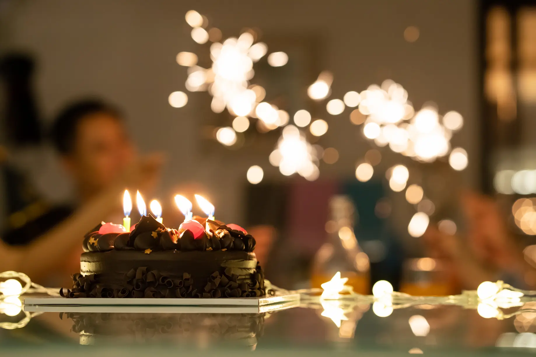 Chocolate cake with lit candles FAQ banner from BakeOra perfect for birthday celebrations