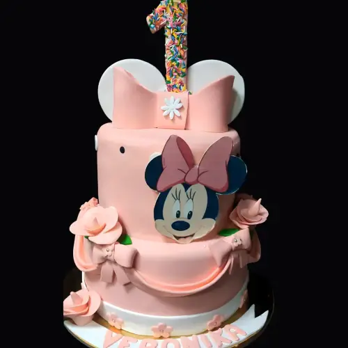 Mini mouse-themed pink and white fondant cake with fondant bow, flowers, and colorful sprinkles