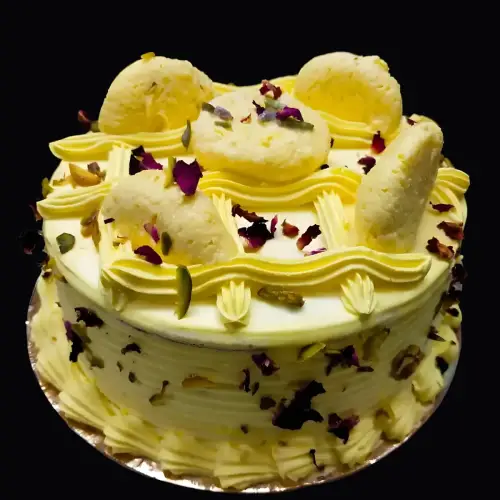 Close-up of layered ras malai cake with almond-pista crunch, rose petals, and creamy frosting