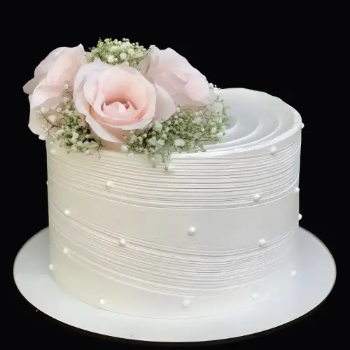 White cake decorated with pink roses, gypsy flowers, and silver sugar pearls