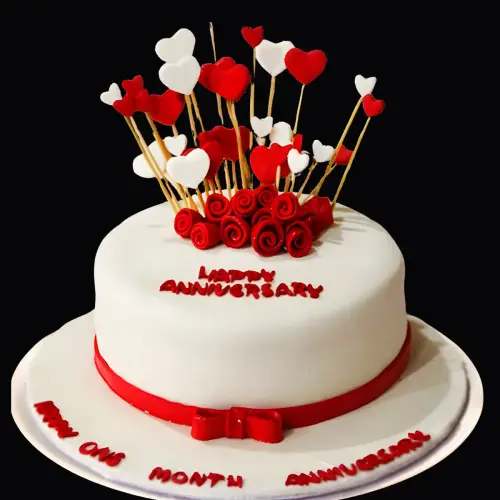 White fondant cake decorated with a red satin bow, red roses, and red and white hearts