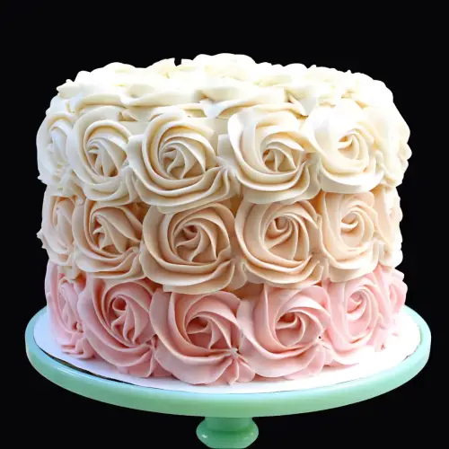 White cake covered in light pink and white roses with delicate petals