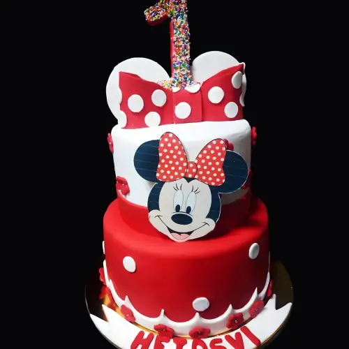 Mini mouse-themed red and white fondant cake with a fondant bow, flowers, and colorful sprinkles